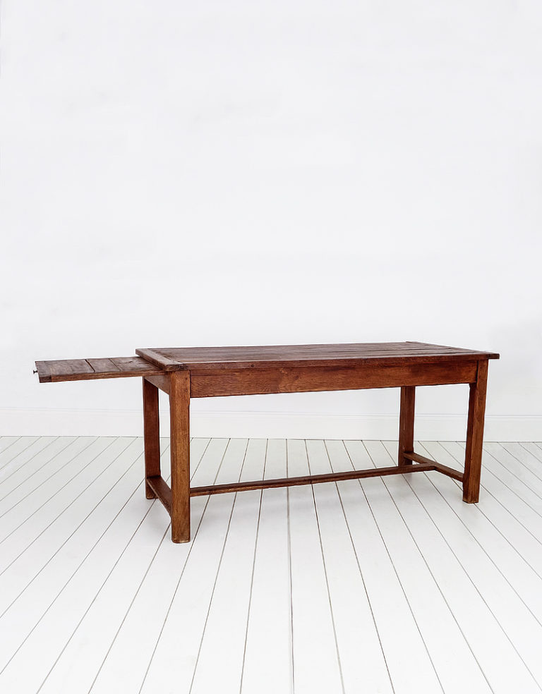 Early oak rustic plank top French farmhouse table, with cleated ends and a sliding breadboard.