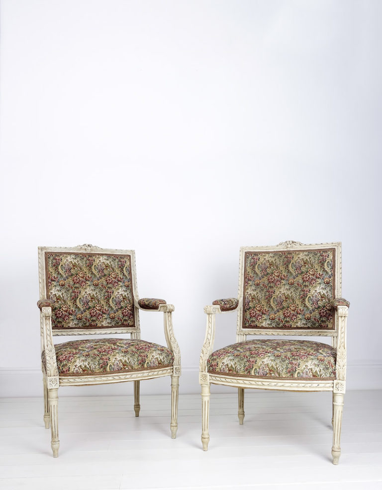 An elegant pair of French Louis XVI style painted open armchairs with delicate carvings, 20th century.