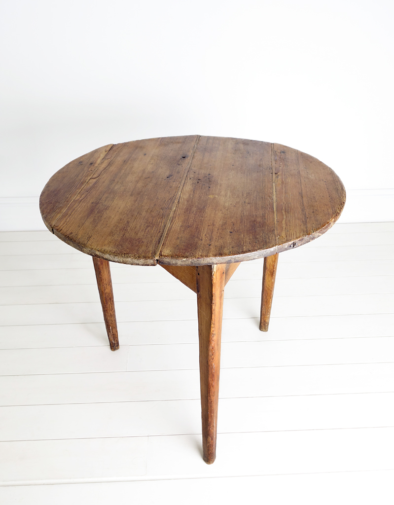 An antique large pine tavern style cricket table. With a four plank circular table top and tapered legs..